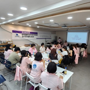 현수막이 걸린 강의실에서 분홍 앞치마를 입고 실습 중인 수강생들
